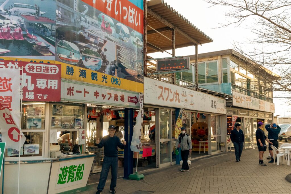 相模湖の静寂、西八王子の熱。仲間と囲む「痛風鍋」で締める、最高の休日。 昭和レトロな雰囲気が漂う、ボート券売り場とゲームセンターが並ぶ商店。