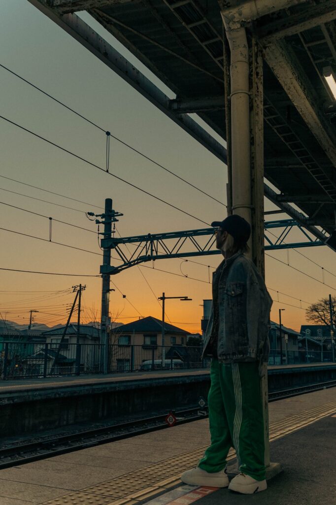 相模湖の静寂、西八王子の熱。仲間と囲む「痛風鍋」で締める、最高の休日。 夕焼け空が広がる駅のホームで、遠くを見つめて佇む人のシルエット。