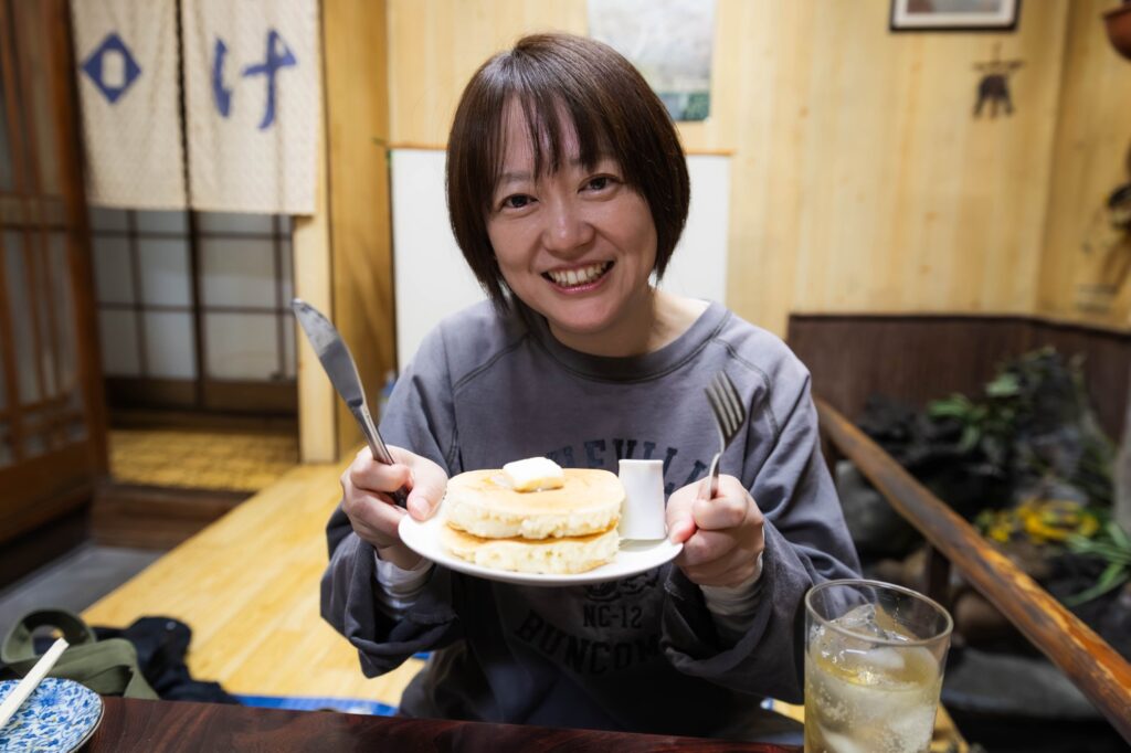 黄色い看板が灯る夜。八王子「夕やけ」で見つけた、昭和の温もり。 hachioji yuyake woman holding hotcake plate smiling
